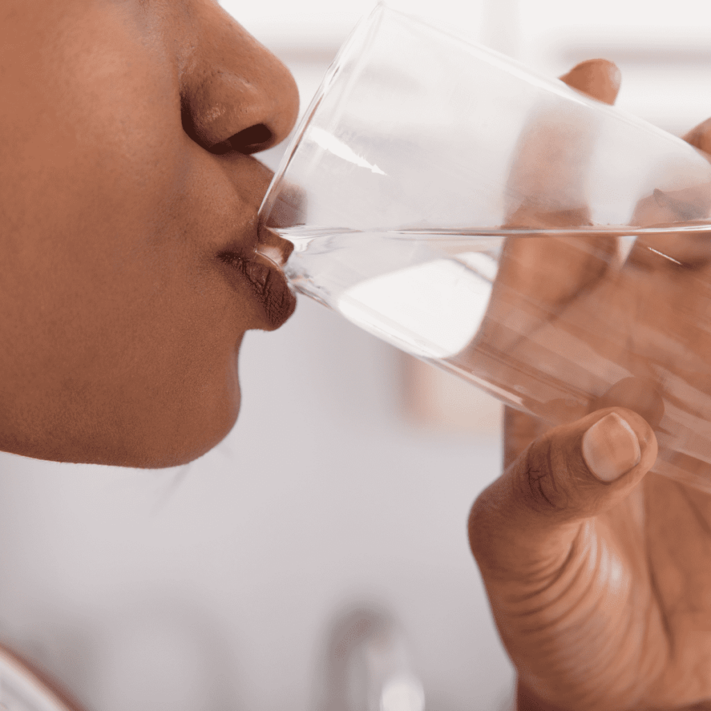 woman drinking filtered water from a clear glass