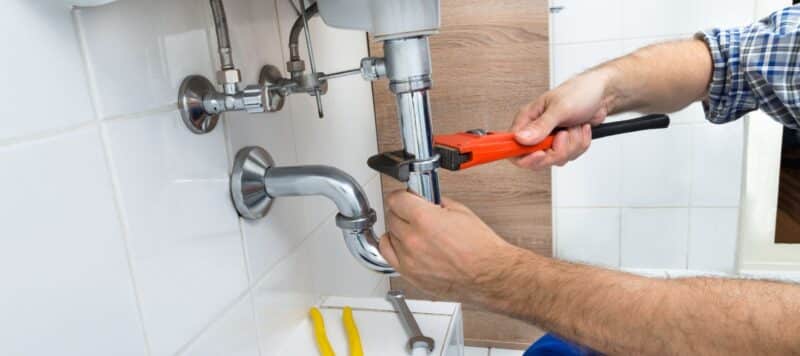 a man using a pipe wrench to tighten a sink pipe