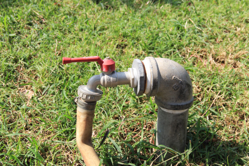 above-ground pipes in a yard with a backflow preventer