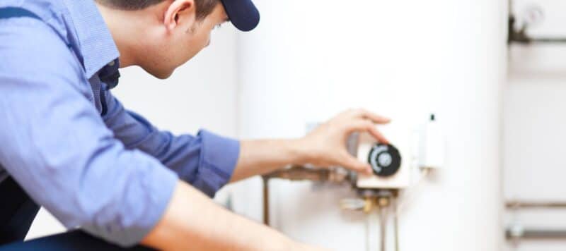 plumber adjusting temperature control knob on white water heater