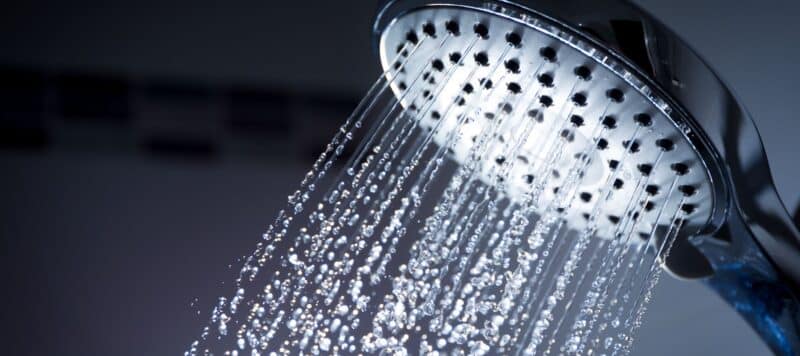 water flowing through a large, round silver showerhead