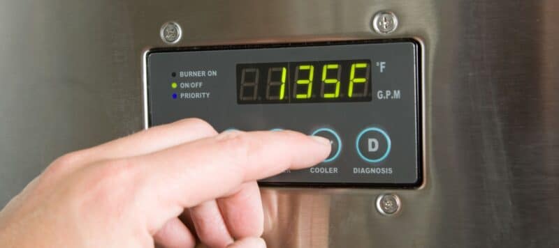 hand adjusting the temperature on a tankless water heater digital control screen