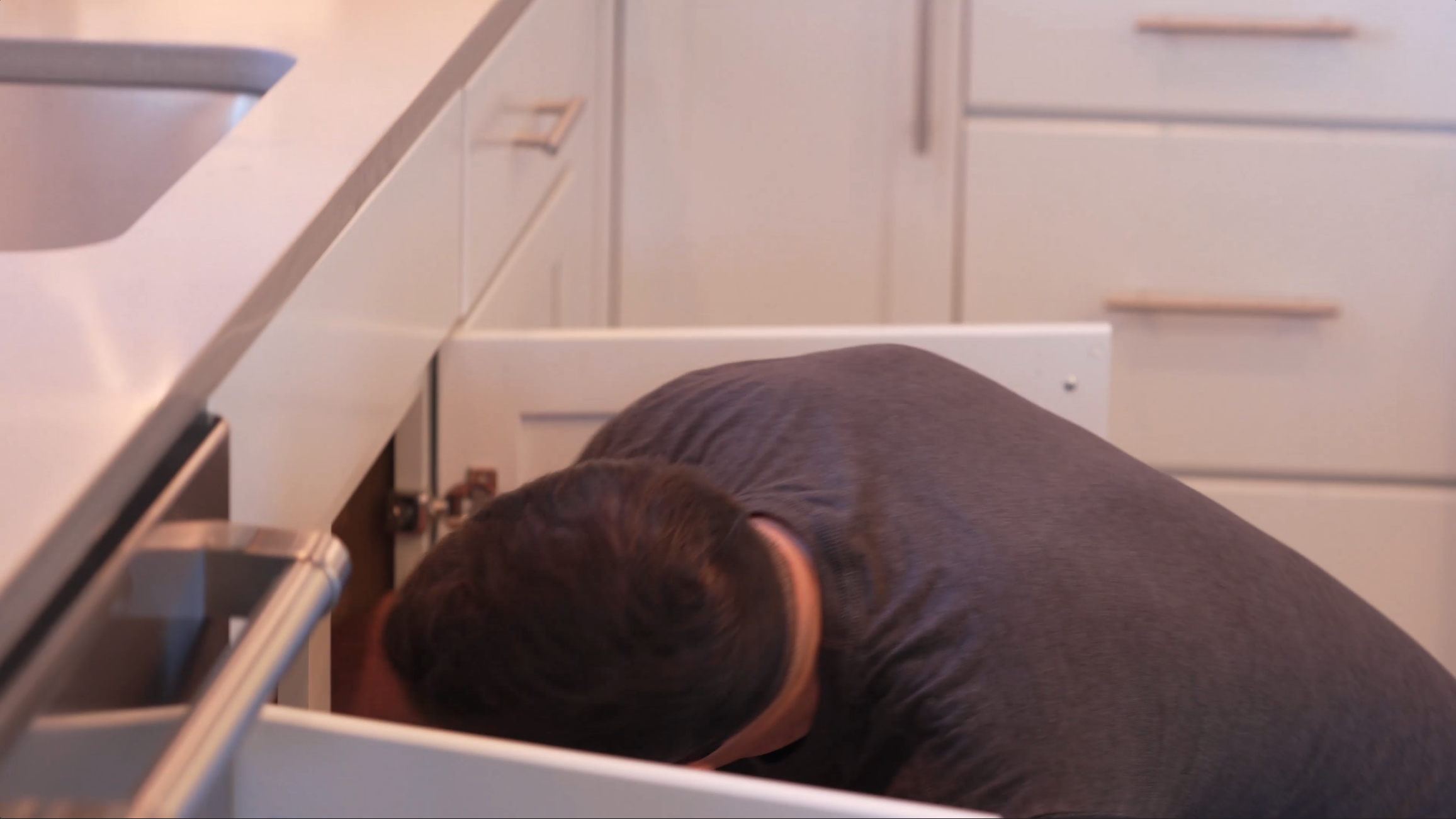 Raptor Rooter & Plumbing plumber working under a bathroom vanity in a Spokane Valley home